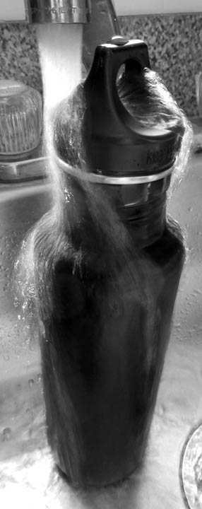 4. Place the bottle in the sink and tighten the cap. Run cold water so that it hits as much of the bottle as possible. Simple physics at work: we're letting the heat escape through the metal and get pulled quickly away by the cold water. Let it run for a few minutes and it should be slightly cool to touch. © 2016 Peter Wetzel.